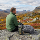 Vandrare tar rast på fjället med vevradion och ryggsäcken på en sten i höstfärger